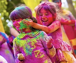 Children laugh and smear the colours on their friends
